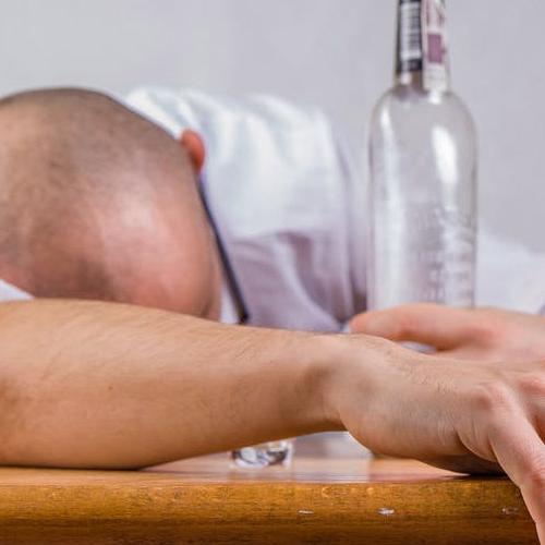 A person face down on a table with a bottle in their hand